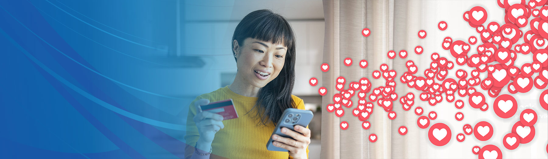 Young woman holds a credit card while looking at her mobile phone with hearts emanating from it.